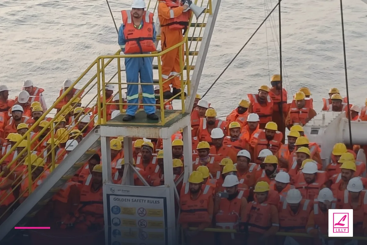 Crew in orange lifejackets beside a yellow vessel stairway, with a navy and magenta Lilly Maritime treatment.